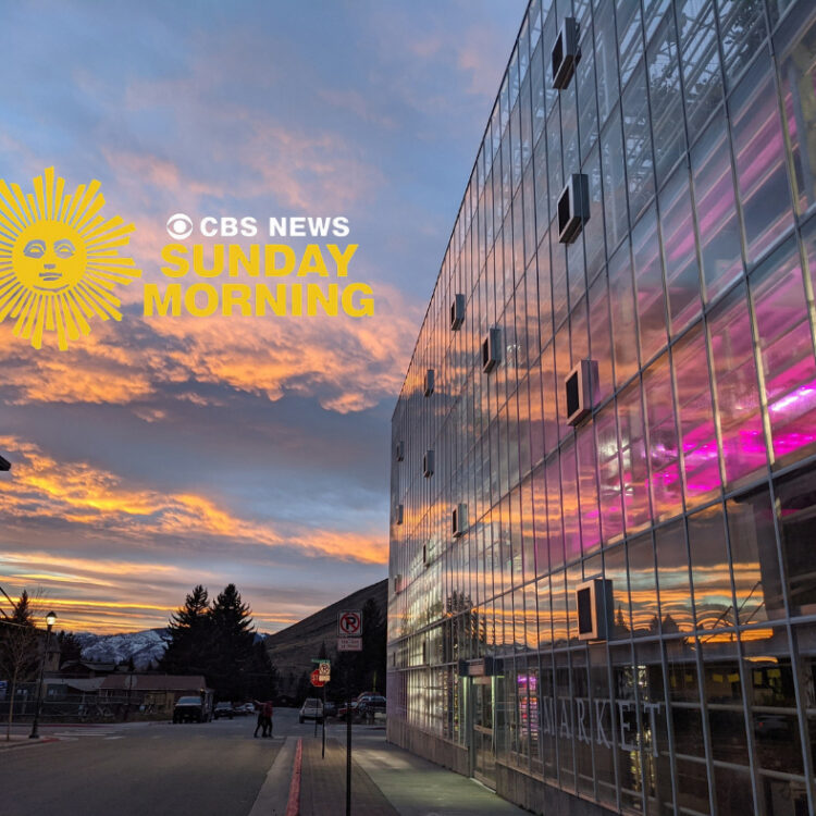 Vertical farm greenhouse with sunset reflected in it's glass exterior with a CBS Sunday Morning logo